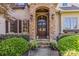 Elegant stone-arched entryway with a wood double door, flanked by greenery and charming details at 9200 Kingsmead Ln, Waxhaw, NC 28173