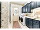 Inviting laundry room with stylish wallpaper, modern washer/dryer, granite counters, and dark blue cabinetry at 9200 Kingsmead Ln, Waxhaw, NC 28173