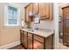 Wet bar with wood cabinets, granite countertop, stainless steel sink, and a window offering natural light at 9200 Kingsmead Ln, Waxhaw, NC 28173