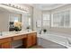 Relaxing bathroom with a soaking tub, large mirror, and natural light from the window at 9715 Aragorn Nw Ln, Charlotte, NC 28269