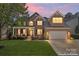 Charming brick home featuring a well-manicured lawn, covered porch, and two-car garage, captured at twilight at 9715 Aragorn Nw Ln, Charlotte, NC 28269