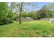 Expansive backyard featuring a home, deck, and bordered by lush trees and a fence at 10340 Williams Rd, Mint Hill, NC 28227