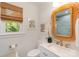 Bright bathroom with a decorative mirror, white vanity, bamboo shade, and soft natural light at 106 Friendfield Dr # B, Fort Mill, SC 29715