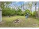 Back yard with fire pit, playground, and scattered trees under a partly cloudy blue sky at 1119 Highway 218 W Hwy, Indian Trail, NC 28079