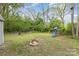 Back yard with fire pit, playground, and scattered trees under a partly cloudy blue sky at 1119 Highway 218 W Hwy, Indian Trail, NC 28079