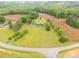 Birds eye view of a house, outbuildings, with a large green yard with scattered trees and farmland beyond at 1162 E Doc Garris Rd, Lancaster, SC 29720