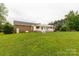 Green backyard with a brick home, a pergola-covered deck, and mature trees at 1162 E Doc Garris Rd, Lancaster, SC 29720