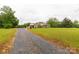 Expansive front yard featuring a brick home with a welcoming porch and gravel driveway at 1162 E Doc Garris Rd, Lancaster, SC 29720