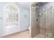 Bright bathroom with a glass shower, window, and neutral tile design at 1233 Weymouth Ln, Charlotte, NC 28270
