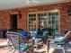 This brick-paved, covered patio features wicker furniture, with views of the backyard at 1233 Weymouth Ln, Charlotte, NC 28270