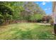Fenced backyard with green lawn, trees, shrubs and an outdoor dining area at 14220 Stewarts Bend Ln, Charlotte, NC 28277