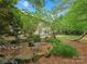 Backyard featuring a hammock, mature trees, fire pit and seating, and lush landscaping at 14220 Stewarts Bend Ln, Charlotte, NC 28277