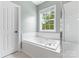 Bright bathroom featuring soaking tub with jets, white tile, and large window at 14220 Stewarts Bend Ln, Charlotte, NC 28277