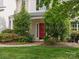 Inviting front porch with a red door, lush landscaping, and a well-maintained walkway at 14220 Stewarts Bend Ln, Charlotte, NC 28277