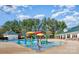 Community pool featuring a splashpad with colorful structures, surrounded by trees and clubhouse facilities at 14220 Stewarts Bend Ln, Charlotte, NC 28277