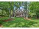 Large backyard featuring mature trees, lush green grass, and an expansive brick patio at 17040 Jetton Rd, Cornelius, NC 28031