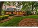 View of backyard featuring a covered patio with stone flooring, manicured lawn, and mature trees, great for outdoor entertaining at 17040 Jetton Rd, Cornelius, NC 28031