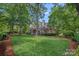 Expansive backyard featuring mature trees and a brick patio with an outdoor living area at 17040 Jetton Rd, Cornelius, NC 28031