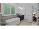 Bright bathroom features a modern soaking tub, vanity with marble countertop and plantation shutters at 17040 Jetton Rd, Cornelius, NC 28031