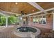 Covered outdoor patio featuring a hot tub, table and chairs, ceiling fans, and brick floors at 17040 Jetton Rd, Cornelius, NC 28031