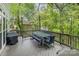 Outdoor deck with a seating arrangement, grill, and wooden railing overlooking the surrounding trees at 1713 Mt Isle Harbor Dr, Charlotte, NC 28214