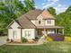 Charming two-story home features a stone and siding exterior, complemented by a covered front porch and landscaped yard at 1713 Mt Isle Harbor Dr, Charlotte, NC 28214
