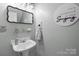 Stylish half bathroom features modern fixtures, decorative mirror, and 'singing' wall art at 230 Castle Keep Rd, Salisbury, NC 28146