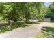 Lovely ranch style home showing a gravel driveway leading to an attached garage surrounded by mature shade trees at 3332 Celanese Rd, Rock Hill, SC 29732