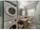 A well-lit bathroom with a stackable washer and dryer, a sink, and tiled walls at 4544 Craig Ave, Charlotte, NC 28211