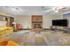 Spacious living room with a brick fireplace, ceiling fan and colorful carpet tiles adding a unique touch at 4935 Kennedy St, Hickory, NC 28602