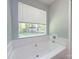 Bright bathroom features a white soaking tub with a view of the backyard through a window at 7731 Ivy Hollow Dr, Charlotte, NC 28227