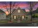 Charming home featuring a picket fence, well-maintained yard, and inviting entrance with stone accents at dusk at 7850 Bud Henderson Rd, Huntersville, NC 28078