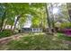 Charming home exterior with a pathway, surrounded by mature trees and colorful azaleas at 7851 Green Cove Ct, Denver, NC 28037