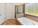Bright bathroom features a soaking tub with tiled surround and a glass block window for natural light at 8708 Soaring Eagle Ln, Waxhaw, NC 28173