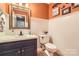 Half bathroom with a white sink, toilet, vanity mirror, and wainscoting at 9517 Harris Glen Dr, Charlotte, NC 28269