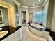 Spacious bathroom featuring a soaking tub, tiled shower, marble floors, and vanity with black countertop at 102 Eastham Ct, Mooresville, NC 28117