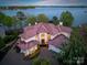 Expansive lakefront home features a red tile roof, manicured landscaping, and a circular driveway at 102 Eastham Ct, Mooresville, NC 28117