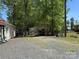 Exterior view of home with gravel parking and carport surrounded by mature trees, offering shade and privacy at 104 Powder Horn Trl # C92, Mount Gilead, NC 27306