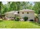 Large backyard featuring a wooden deck, stone patio, and lush green lawn under mature trees at 1043 Nancy Dr, Charlotte, NC 28211
