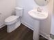 Bright half bathroom features a pedestal sink, toilet, and wood-look flooring at 1075 South Point Rd, Belmont, NC 28012