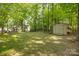 Expansive backyard with mature trees, a storage shed, and ample space for outdoor activities at 110 River Wood Dr, Fort Mill, SC 29715
