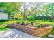Beautiful backyard featuring a stone retaining wall, flower garden, lush lawn and mature trees at 113 Princess Ln, Dallas, NC 28034
