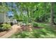 Green backyard featuring a patio with a firepit and an outdoor dining area, surrounded by trees and grass at 1202 Foxfield Rd, Waxhaw, NC 28173