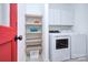 Functional laundry room with new white washer and dryer, custom wood shelving, and red accent door at 1202 Foxfield Rd, Waxhaw, NC 28173