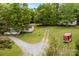 Aerial view of two homes on a large lot with mature trees, gravel driveway and a red trailer at 124 Neumann Run, Belmont, NC 28012
