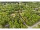 Aerial view of a secluded wooded property with a long driveway and various buildings, backing to a rural road at 124 Neumann Run, Belmont, NC 28012