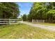 Gravel driveway lined with a white fence and trees, marking the entrance to a private and serene property at 124 Neumann Run, Belmont, NC 28012