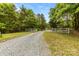 A crushed gravel driveway leading to a beautiful white picket gate surrounded by trees at 124 Neumann Run, Belmont, NC 28012