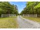 White country style gate and gravel driveway framed by trees at 124 Neumann Run, Belmont, NC 28012