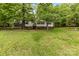 Quaint home nestled among mature trees, showcasing a well-maintained lawn at 124 Neumann Run, Belmont, NC 28012